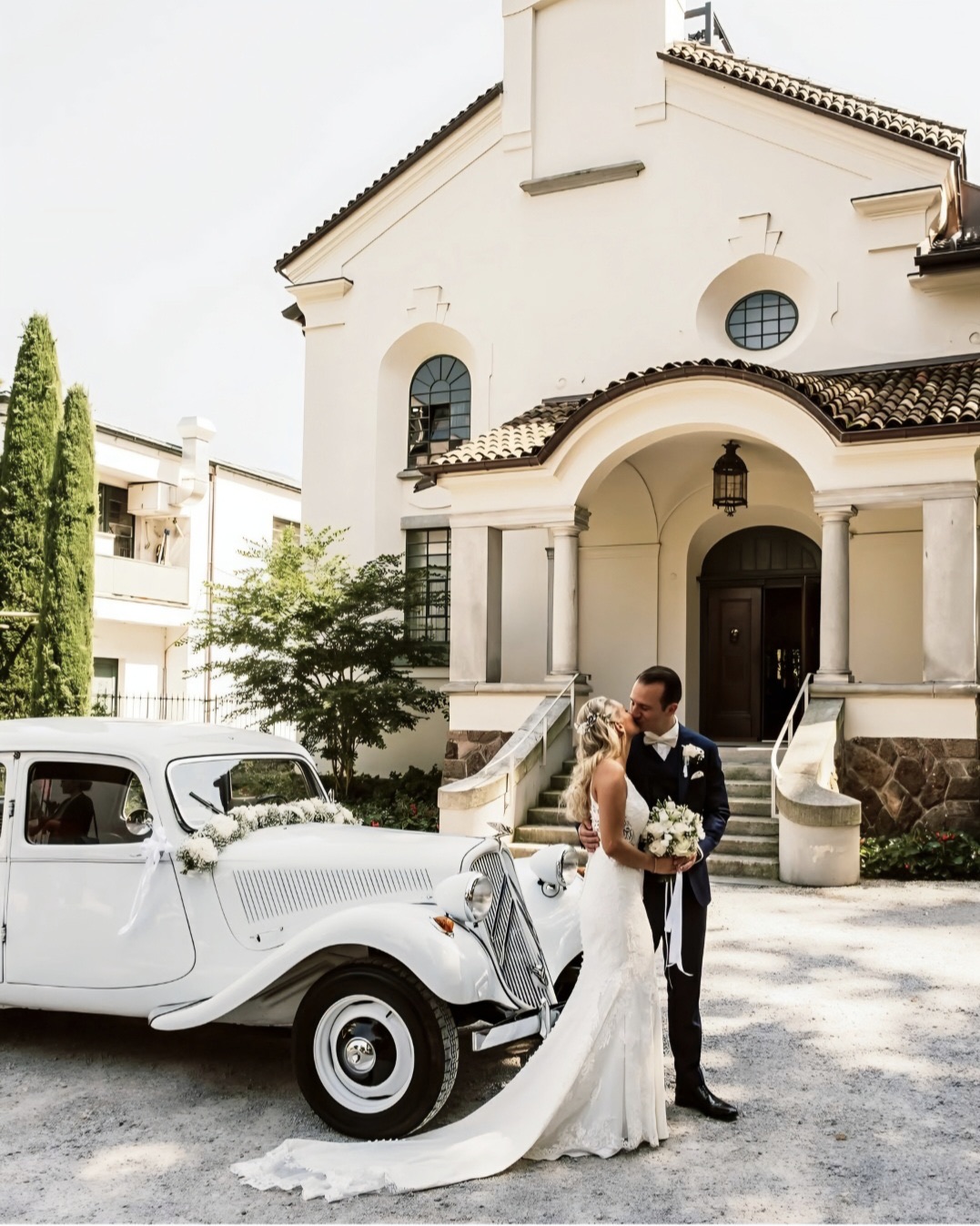 Bacio degli sposi davanti alla chiesa, accanto alla vettura